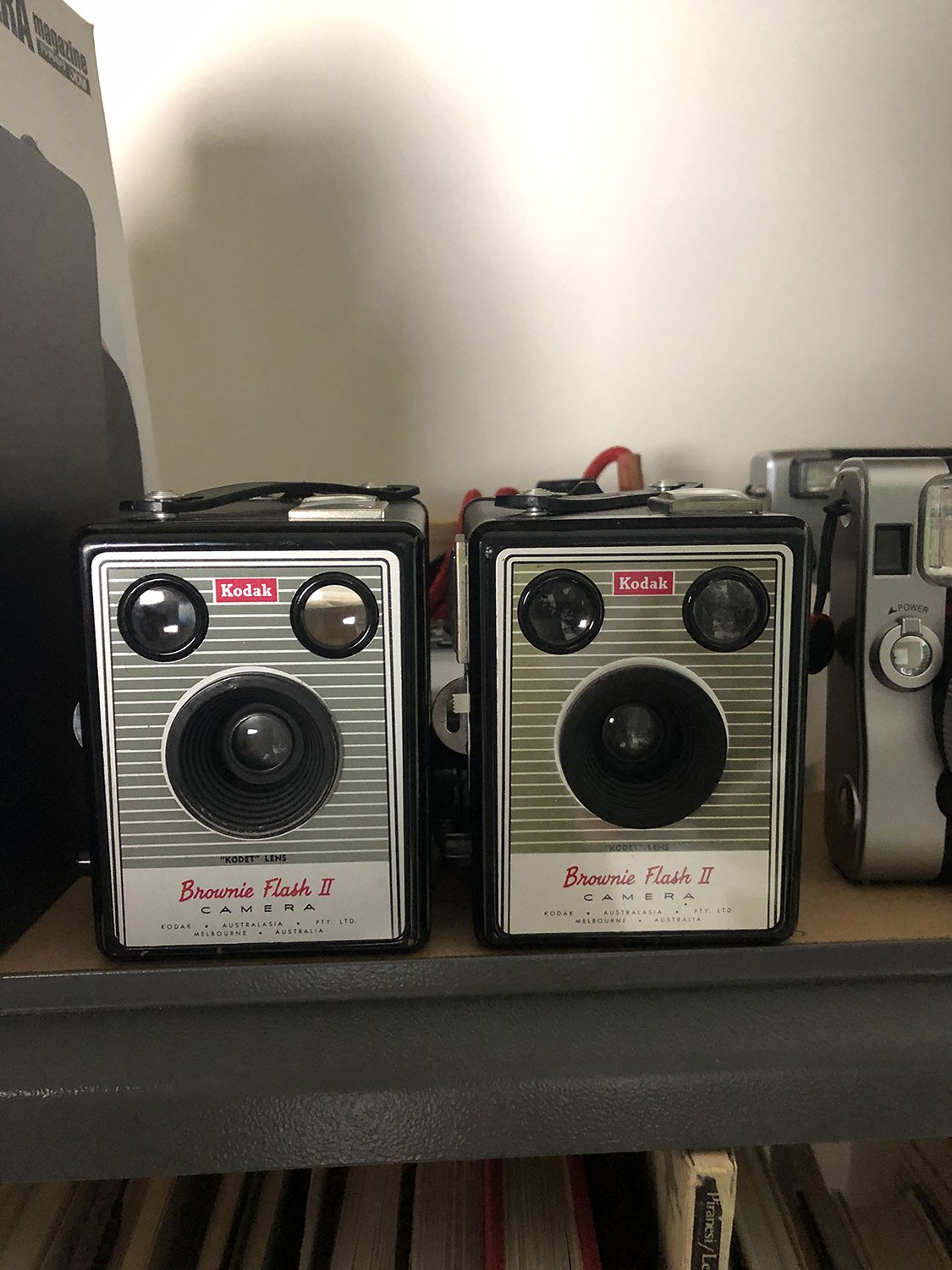 책장 위에 나란히 놓인 Kodak Brownie Flash II 두 대.