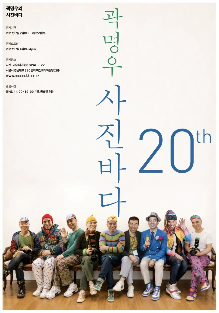 곽명우 〈사진바다〉 포스터. 밝은 크림색 벽 아래 벤치에 알록달록한 모자와 옷을 입은 사진가 아홉 명이 나란히 앉아 손을 흔들며 웃고 있고, 위쪽에 세로로 '곽명우 사진바다'와 파란 20th 글씨가 있다.