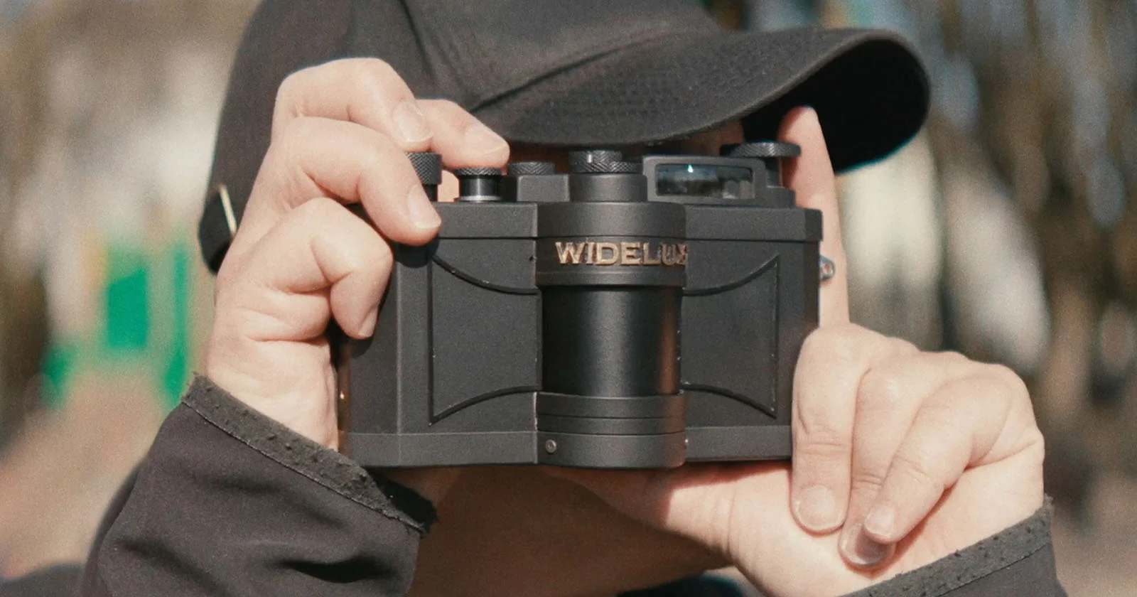 검정 마감의 WideluxX 를 야외에서 양손으로 들고 있는 모습